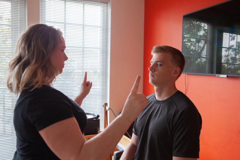 Physical therapist checking a patient's eye tracking during a concussion assessment