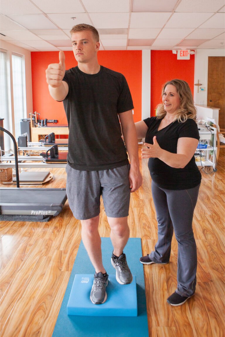 Patient balancing on one leg on a foam pad while tracking his thumb, a vestibular exercise in concussion rehab